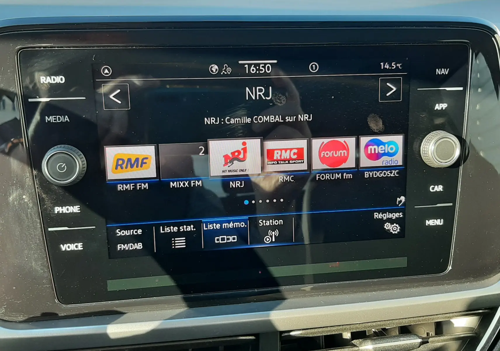 Écran tactile central du Volkswagen T-Roc 2022 affichant les stations radio, avec commandes autour et reflets visibles.