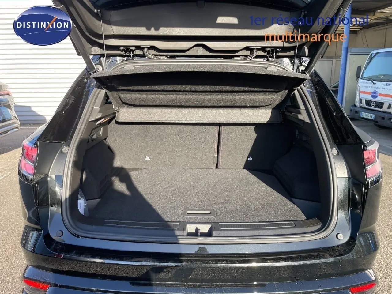 Coffre ouvert vu de l'arrière d'un Renault Austral noir étoile métal, montrant l'espace de chargement vide.