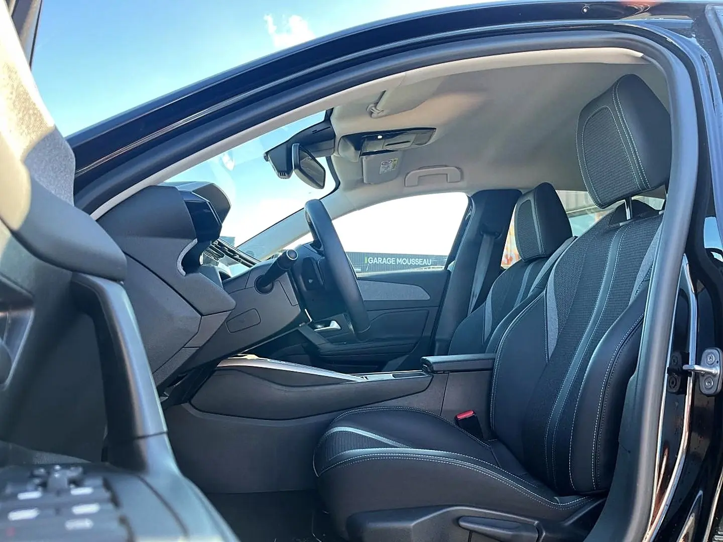 Vue intérieure côté conducteur de la Peugeot 308 noire 2025, mettant en valeur les sièges et le tableau de bord moderne.