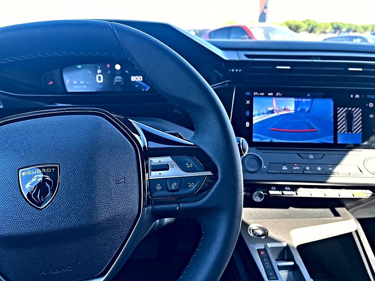 Vue intérieure centrée sur le volant Peugeot noir et l'écran tactile affichant la caméra de recul de la 308 1.5 BlueHDi 2025.