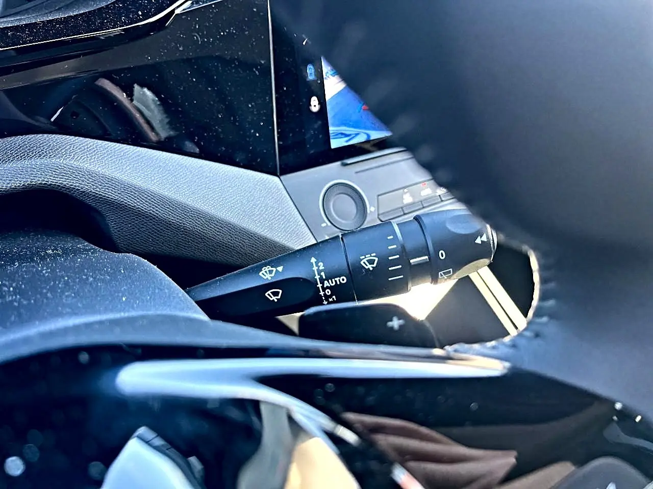 Détail du commodo d’essuie-glace et partie du volant noir dans l’habitacle d’une Peugeot 308 noire 2025.