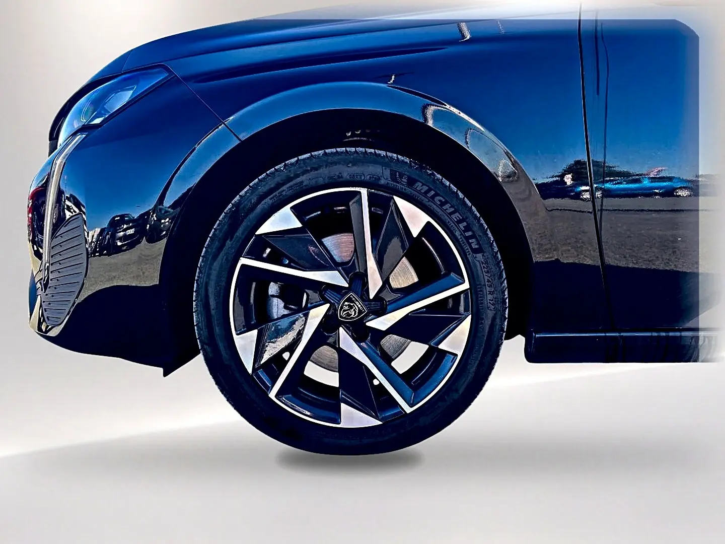 Gros plan sur la roue avant gauche noire d'une Peugeot 308 2025, mettant en valeur la jante alu au design moderne.