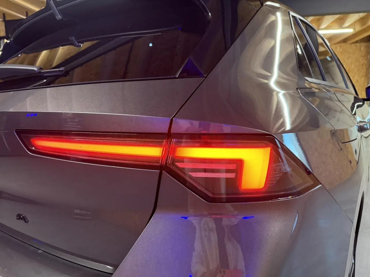 Gros plan sur le feu arrière droit d’une Opel Astra gris foncé, soulignant les lignes modernes et le vitrage surteinté.