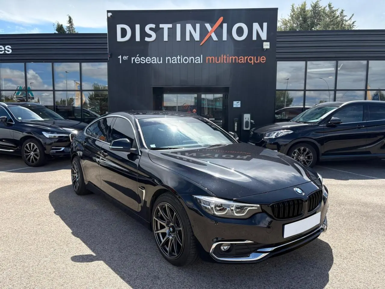 BMW Série 4 Gran Coupé noir saphir vue 3/4 avant droit avec jantes alliage et calandre chromée devant concessionnaire Distinxion