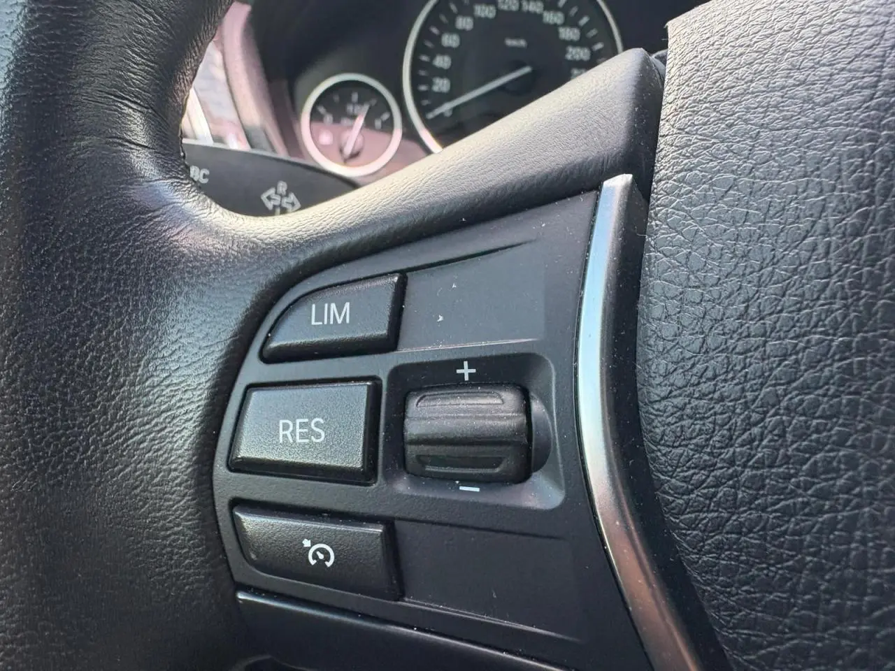 Gros plan sur les commandes du régulateur de vitesse au volant cuir noir d'une BMW Série 4 Gran Coupé 420d.