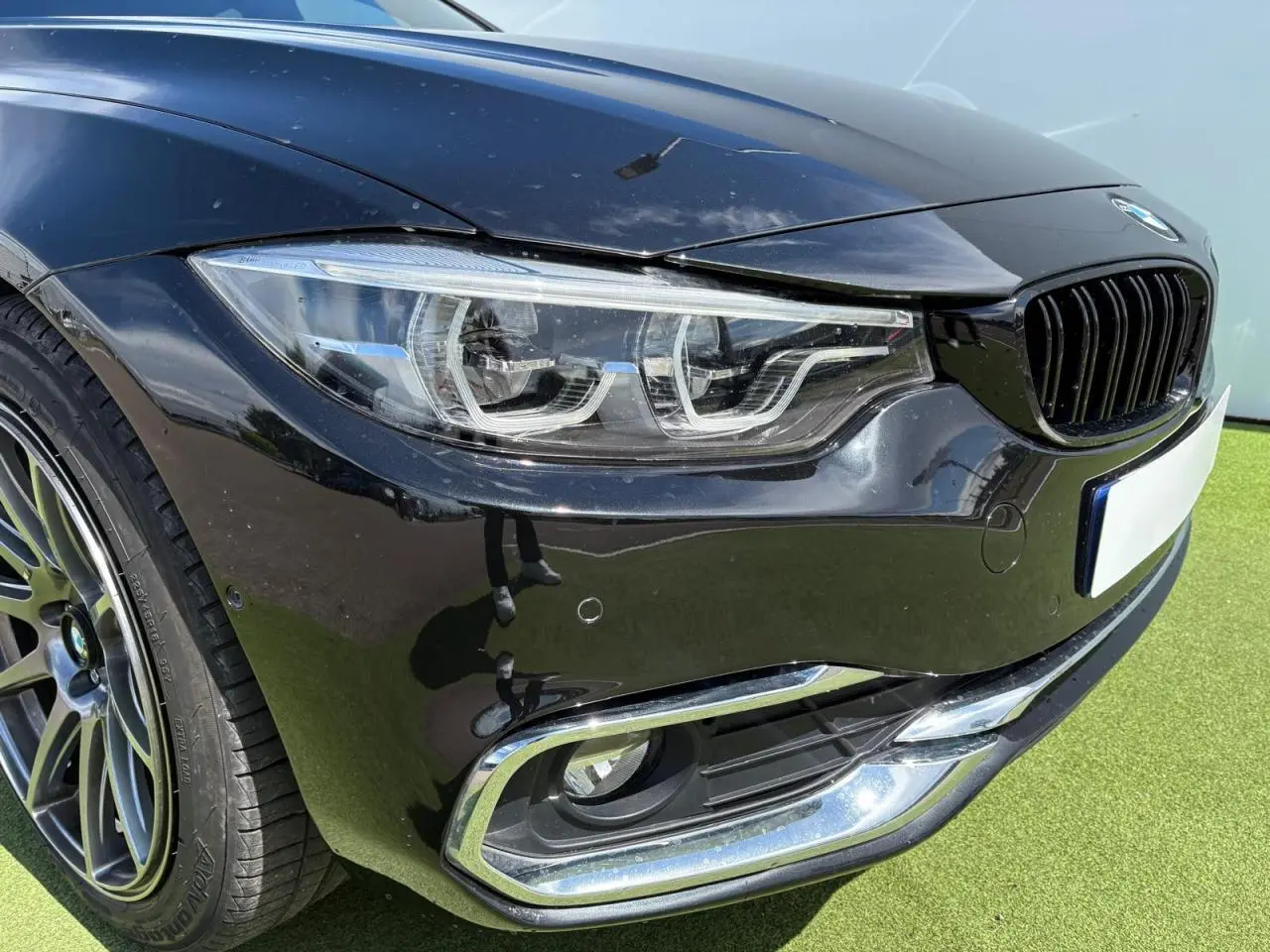 Gros plan sur l'avant droit noir saphir d'une BMW Série 4 Gran Coupe avec phares Full LED et jante alliage 18 pouces.