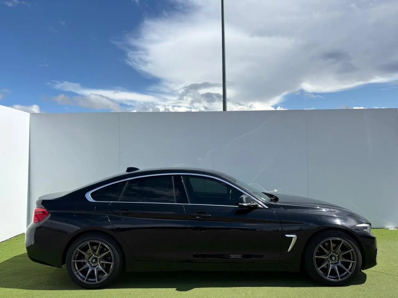 Profil côté gauche d'une BMW Série 4 Gran Coupé 420d noir saphir avec jantes alliage 18 pouces et vitres teintées.