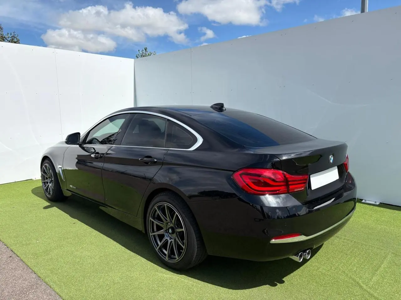 BMW Série 4 Gran Coupé noir saphir vue 3/4 arrière droit avec jantes alliage et double sortie d’échappement chrome
