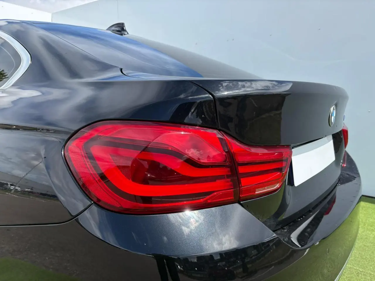 Feu arrière gauche en gros plan d'une BMW Série 4 Gran Coupé 420d noir saphir, reflet sur la carrosserie lisse.
