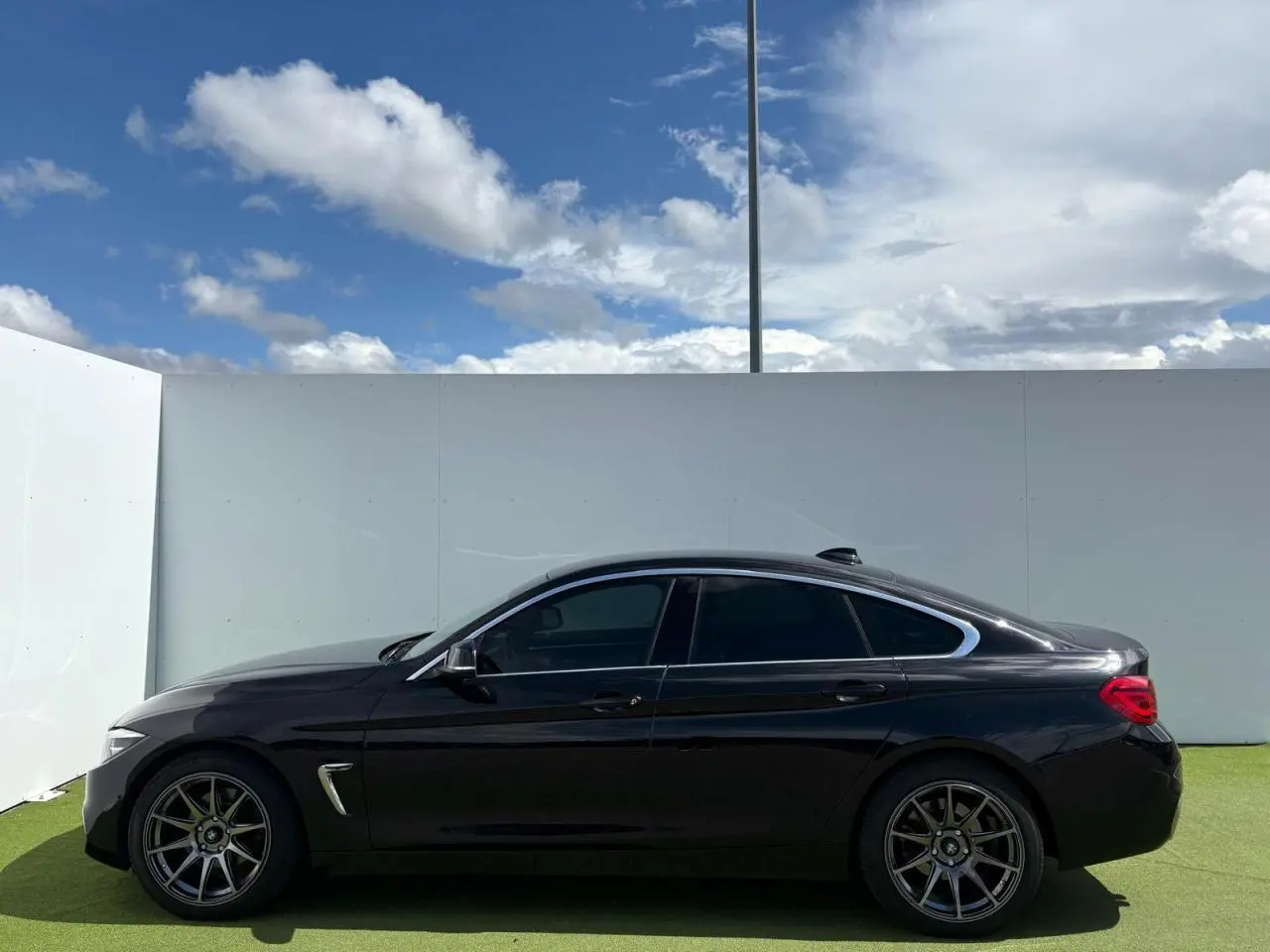 BMW Série 4 Gran Coupé noir saphir vue de profil côté gauche, avec jantes alliage 18 pouces et toit ouvrant.