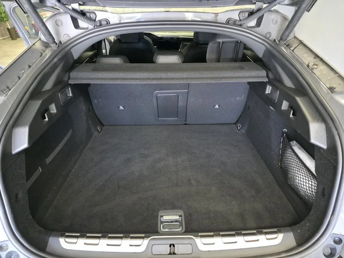 Coffre spacieux vu de l'arrière d'une Peugeot 408 gris, avec banquette arrière et filet de rangement visible.