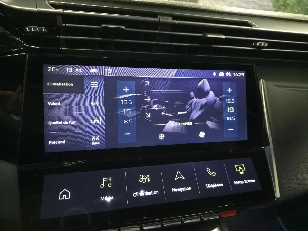 Écran tactile central affichant la climatisation et les réglages du volant dans l'habitacle noir du Peugeot 408 gris