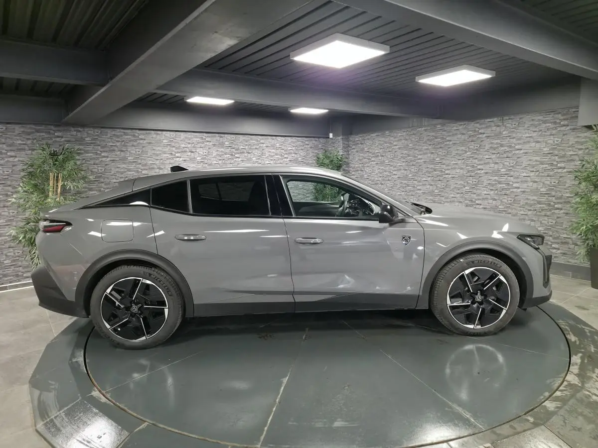 Profil côté gauche de la Peugeot 408 gris métallisé 2024 avec jantes alliage 19 pouces et toit noir Mistral.