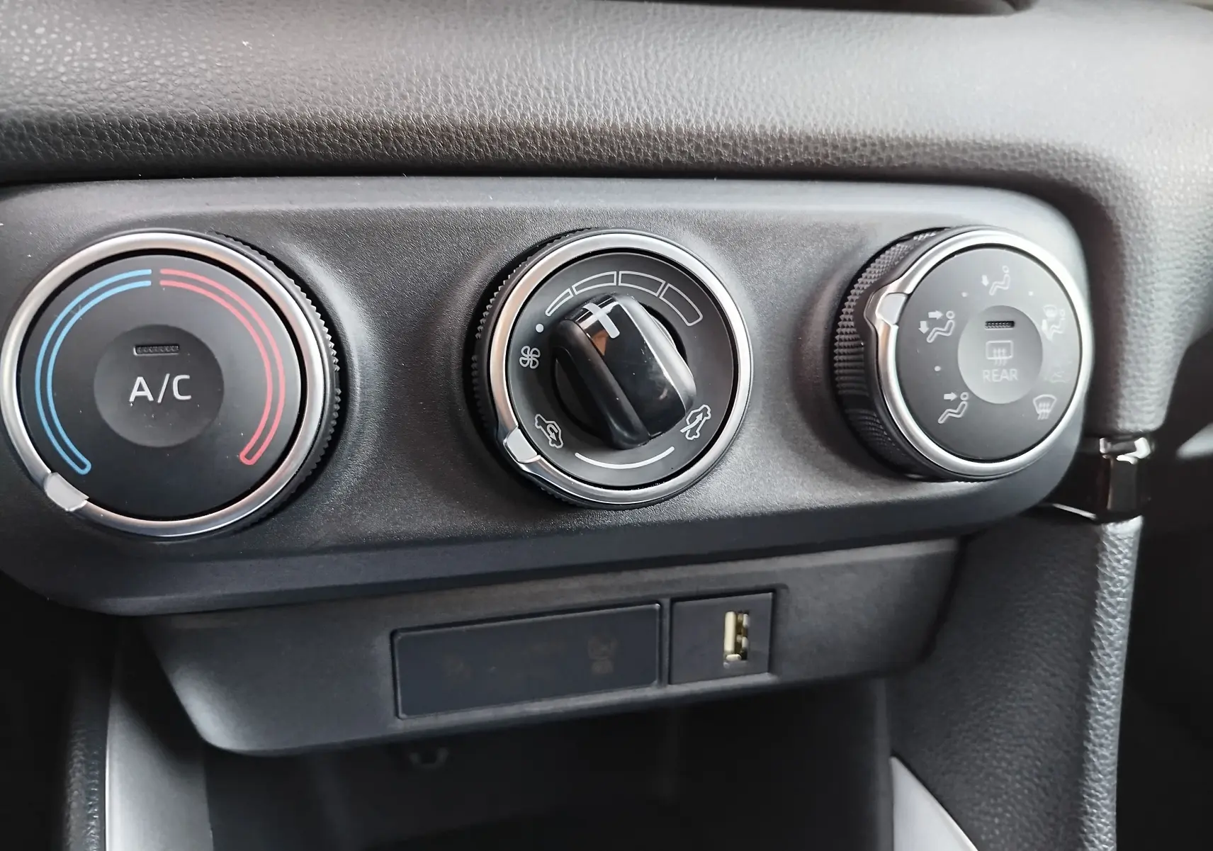 Gros plan sur les commandes de climatisation noires et grises de la Toyota Yaris blanche, version Dynamic Business 2023.