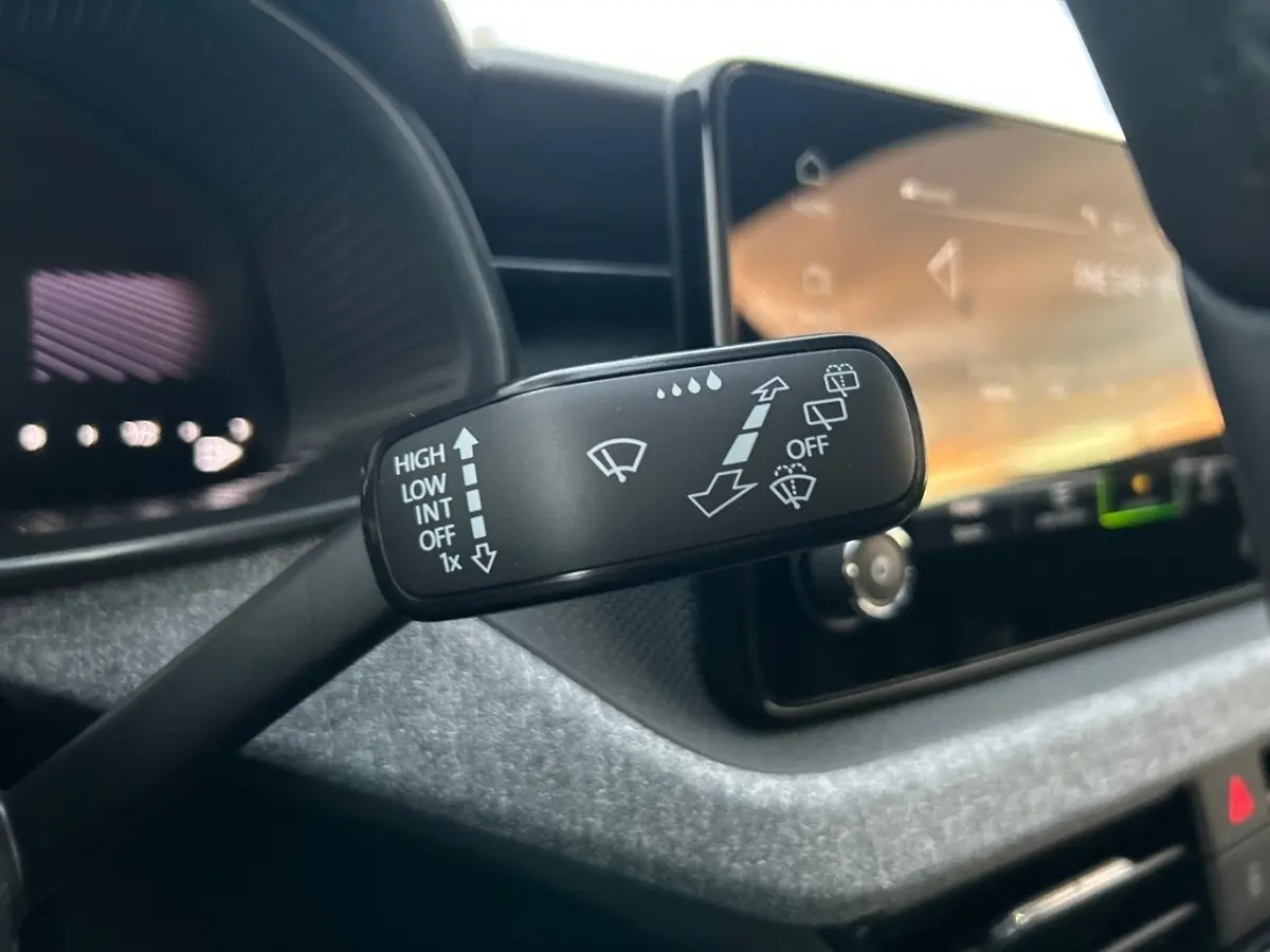 Gros plan sur la commande d'essuie-glace à gauche du volant dans l'habitacle gris clair du Skoda Kamiq 2025.