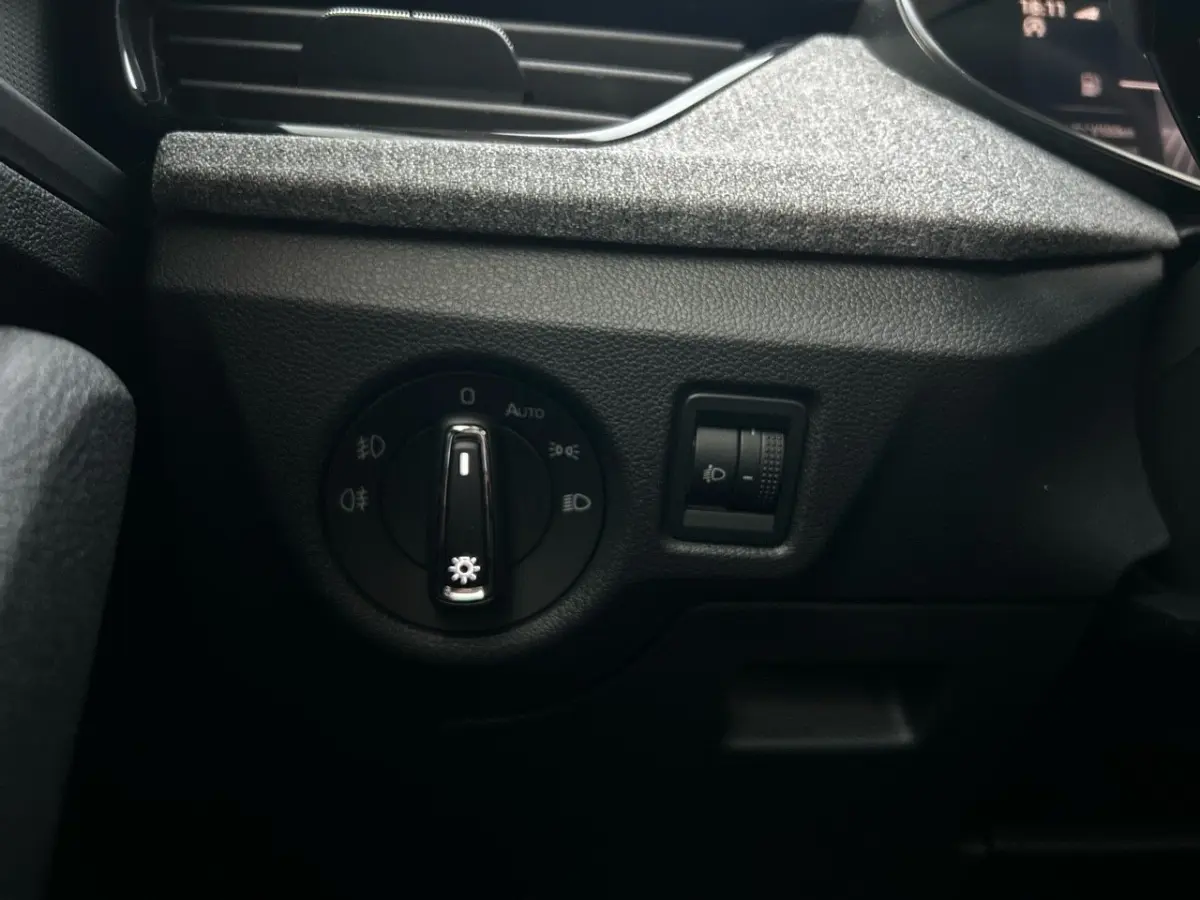 Gros plan sur les commandes d'éclairage côté gauche du tableau de bord noir du Skoda Kamiq gris clair 2025