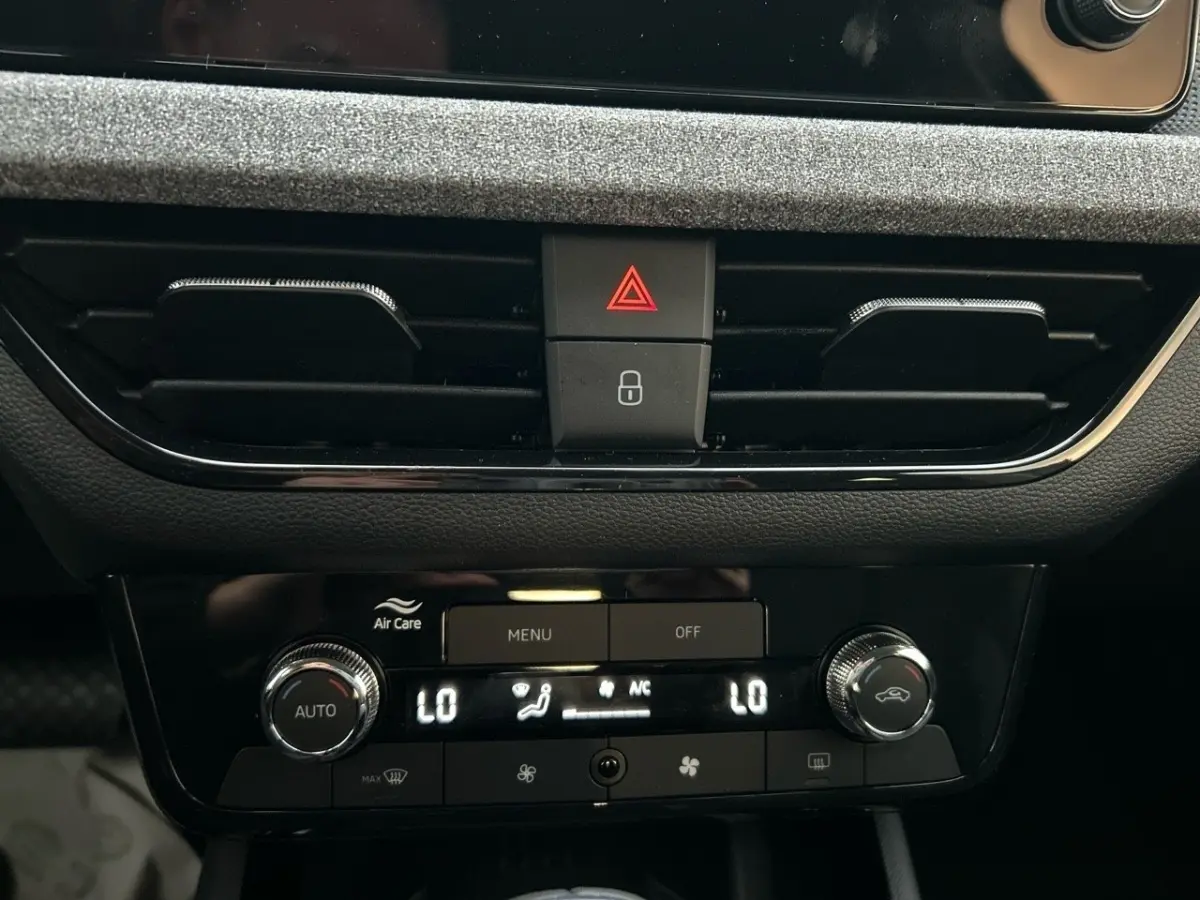 Détail du tableau de bord central noir du Skoda Kamiq 2025 montrant la commande de climatisation automatique bi-zone et les boutons d'alerte.