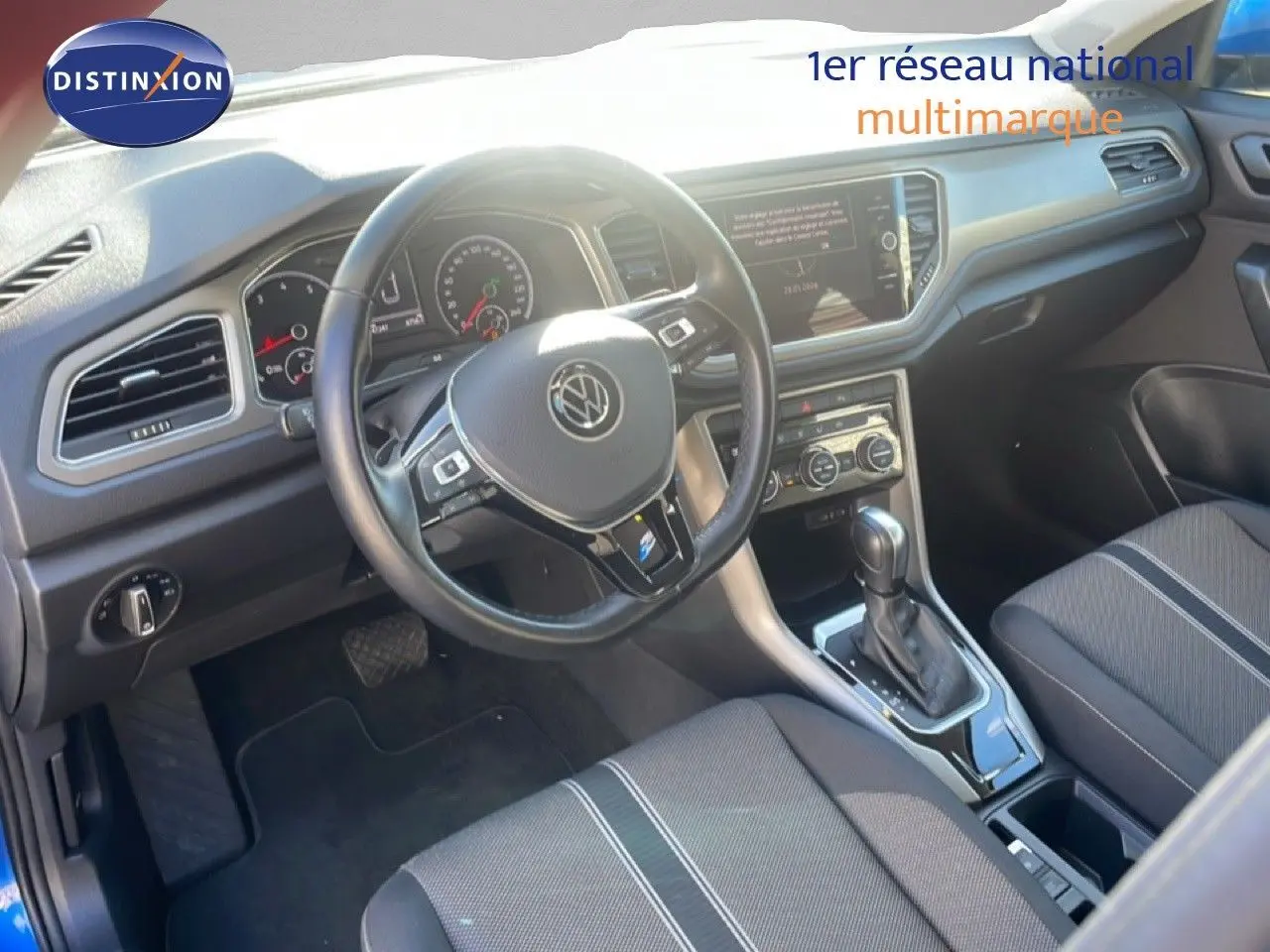Vue intérieure du Volkswagen T-Roc 1.5 TSI 2021, montrant le volant, la console centrale et les sièges en tissu noir.