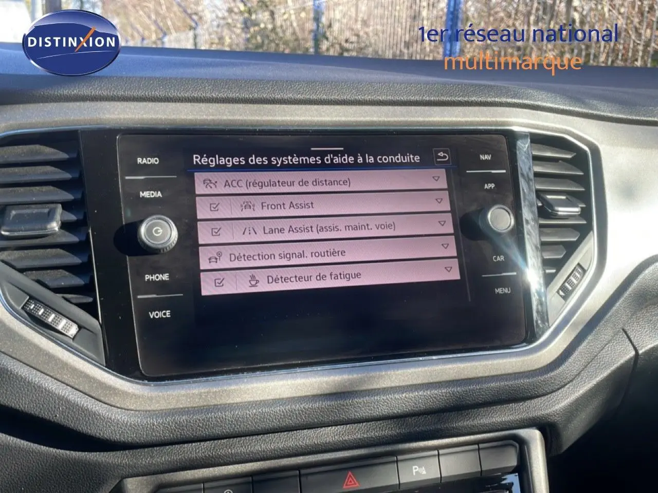 Écran central du tableau de bord du Volkswagen T-Roc 1.5 TSI bleu, affichant les réglages d’aides à la conduite.