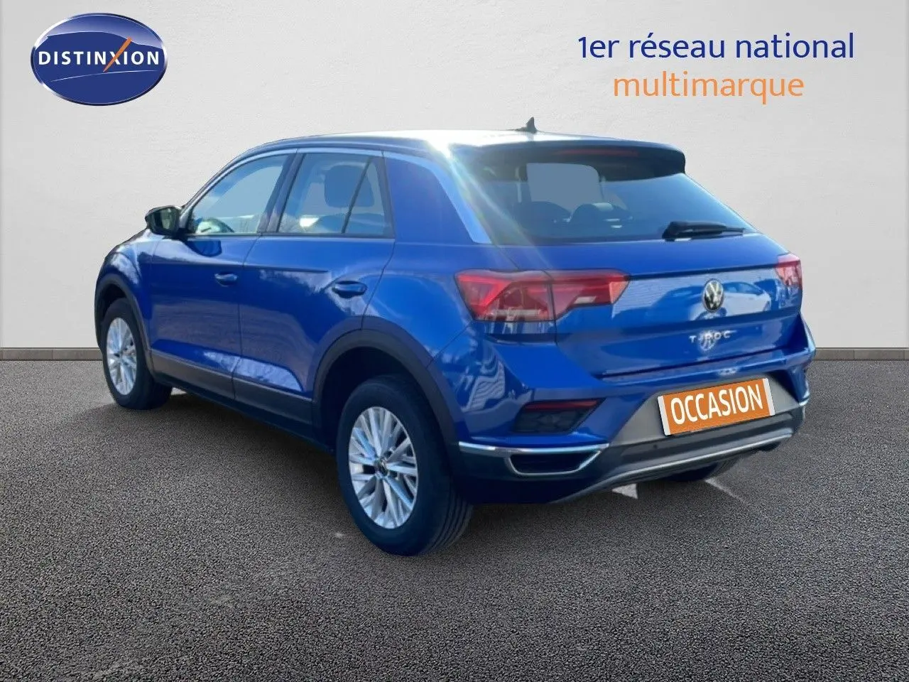 Vue 3/4 arrière droite d'un Volkswagen T-Roc bleu Ravenna métallisé avec jantes alliage et toit noir.