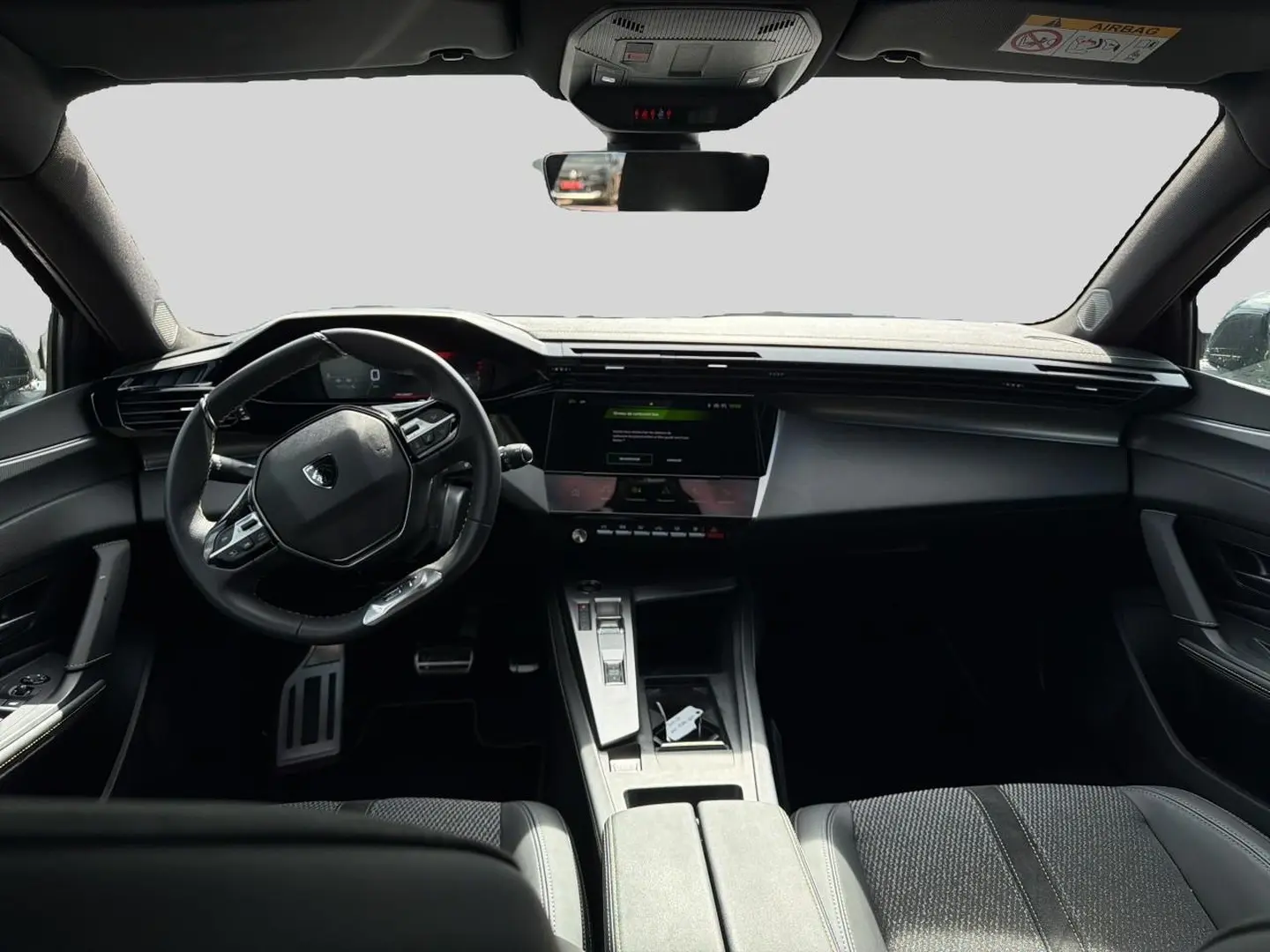 Intérieur noir de la Peugeot 308 1.2 hybrid 145 GT, vue de face sur le tableau de bord et volant multifonction.