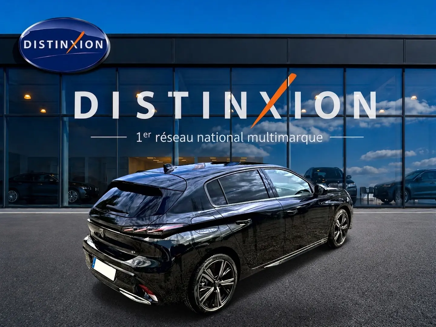 Vue 3/4 arrière droite d'une Peugeot 308 noire 2025 garée devant une vitrine Distinxion, jantes alliage visibles.