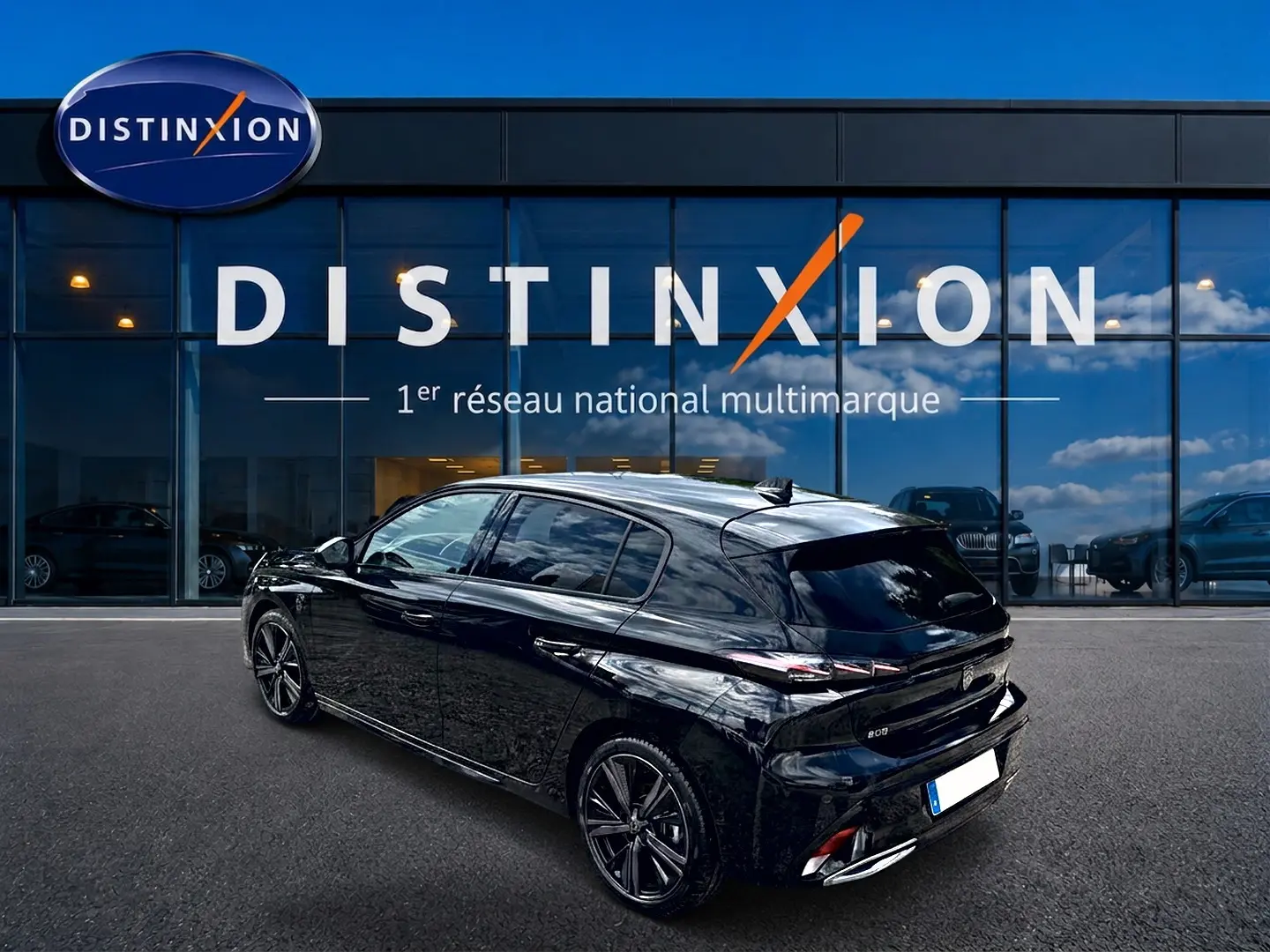 Peugeot 308 1.2 hybrid 145 GT noir vue 3/4 arrière droit, jantes alu et vitres surteintées devant un showroom Distinxion.