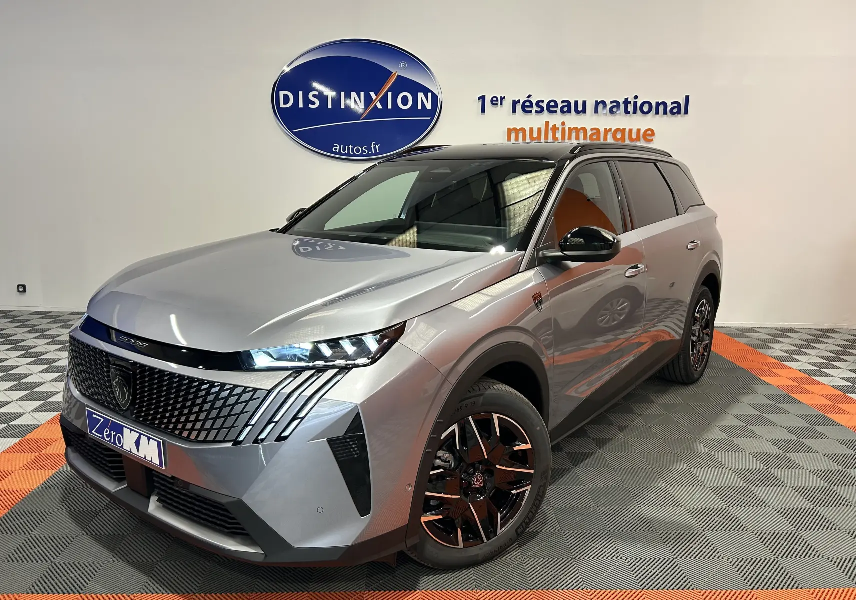 Peugeot 5008 III GT Hybrid gris Artense en 3/4 avant droit, avec jantes bi-ton et calandre distinctive.