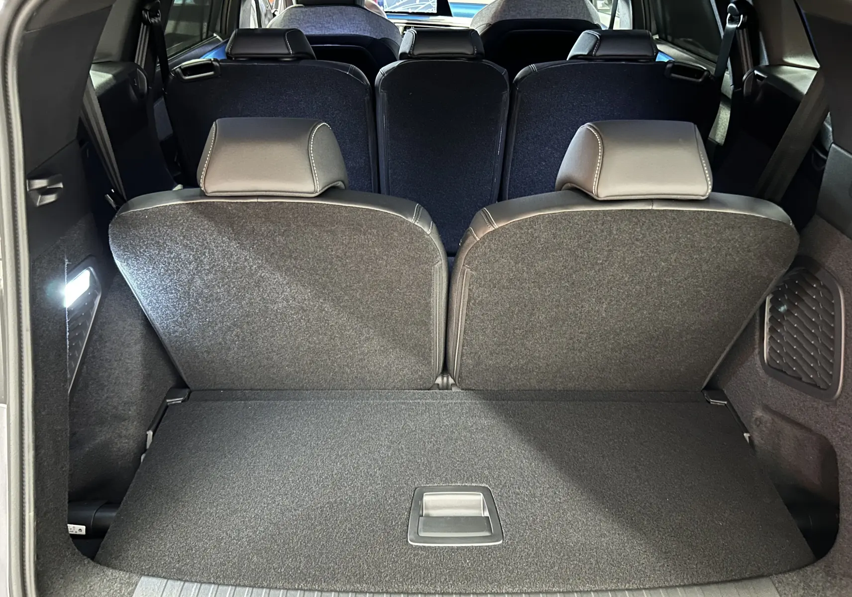 Coffre ouvert montrant la troisième rangée de sièges rabattus du Peugeot 5008 gris Artense, vue arrière intérieure.