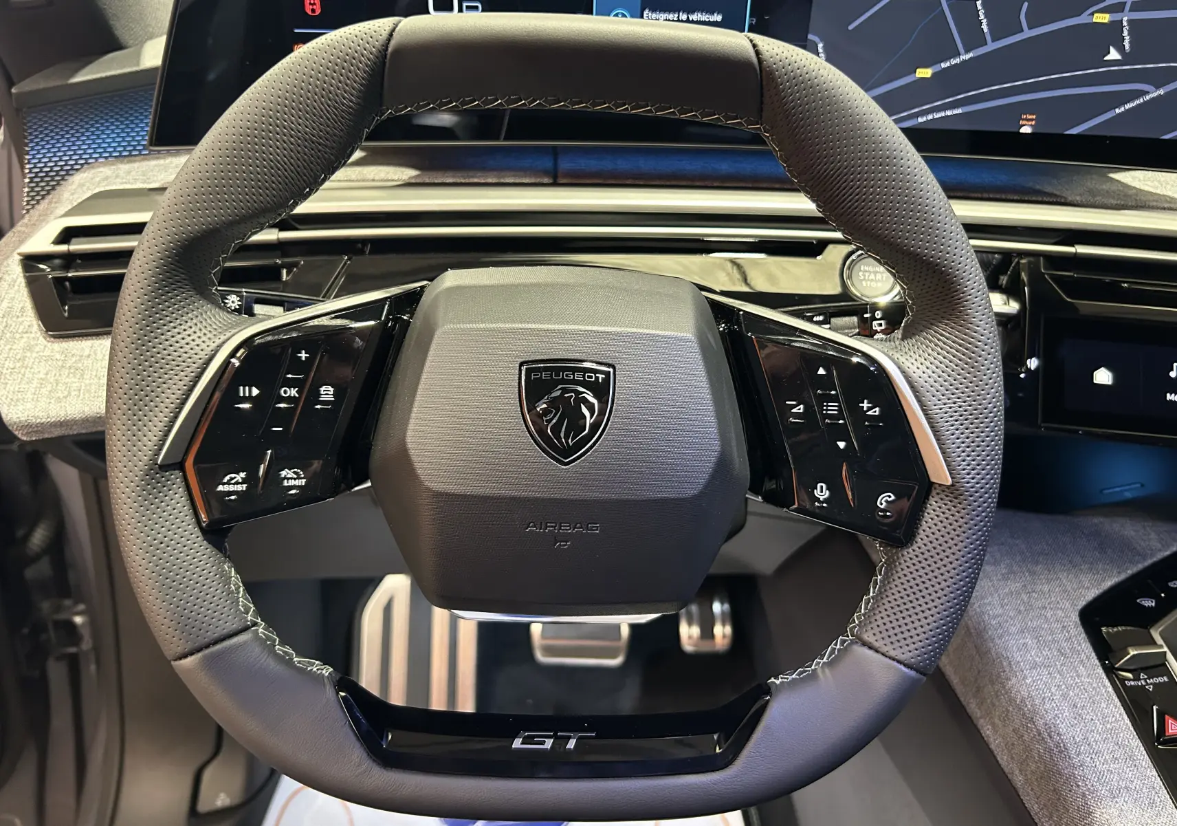 Gros plan sur le volant GT perforé et multifonction du Peugeot 5008 III Hybrid avec tableau de bord numérique.