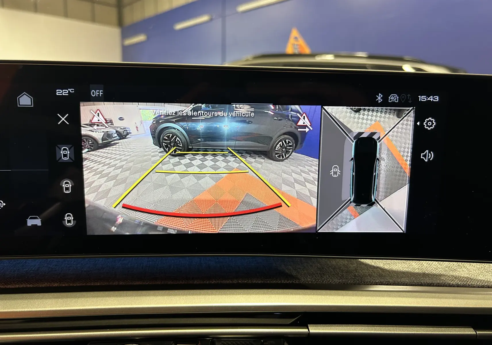 Écran multimédia montrant la caméra de recul et la vue 360° d'un Peugeot 5008 gris Artense en stationnement intérieur.