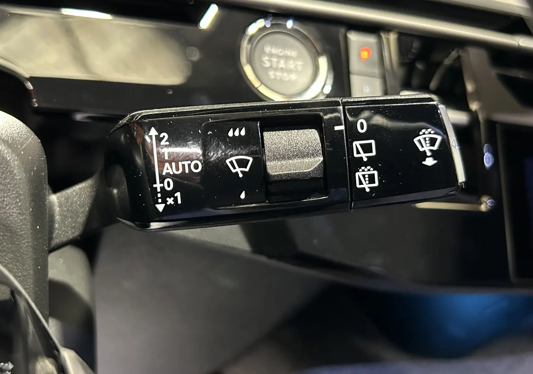 Gros plan sur la commande des essuie-glaces du Peugeot 5008 gris Artense, avec bouton démarrage visible en arrière-plan.
