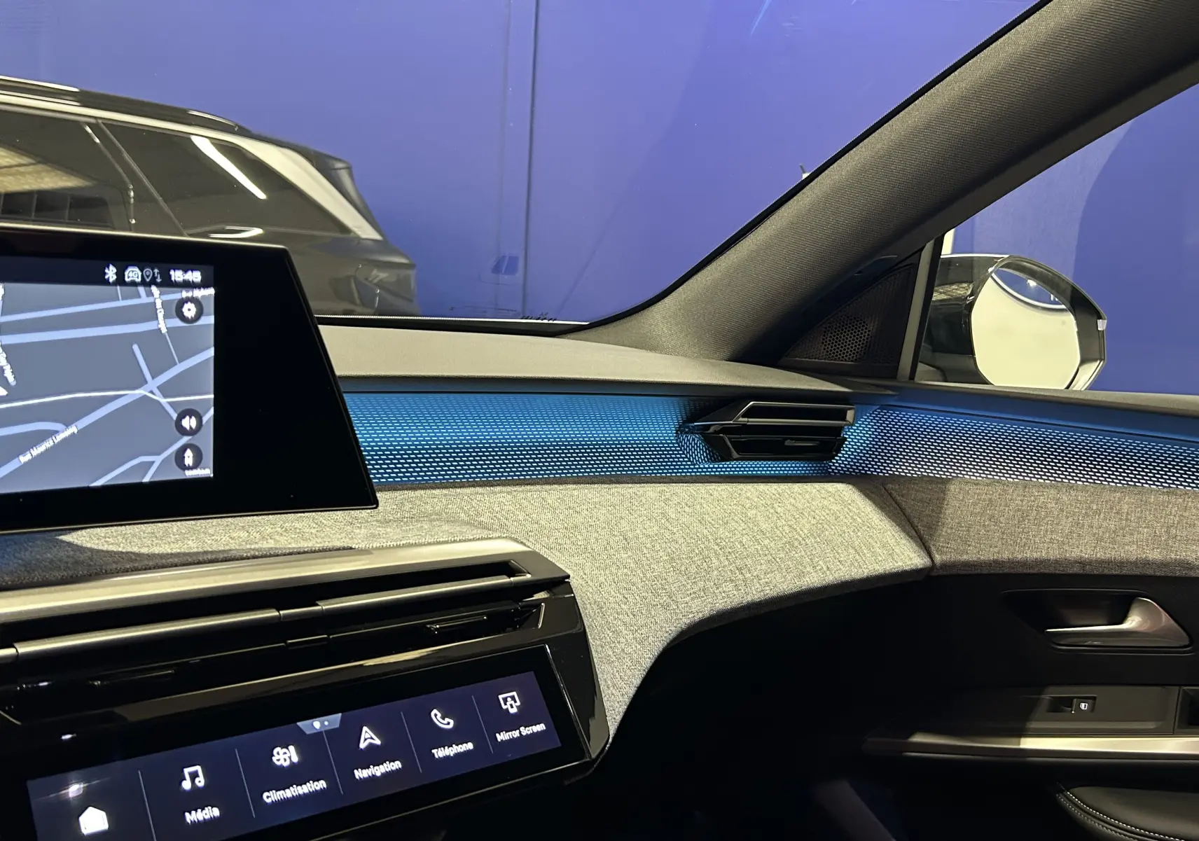 Intérieur du Peugeot 5008 III GT Hybrid 145, vue côté passager avec tableau de bord gris et éclairage bleu ambiance.