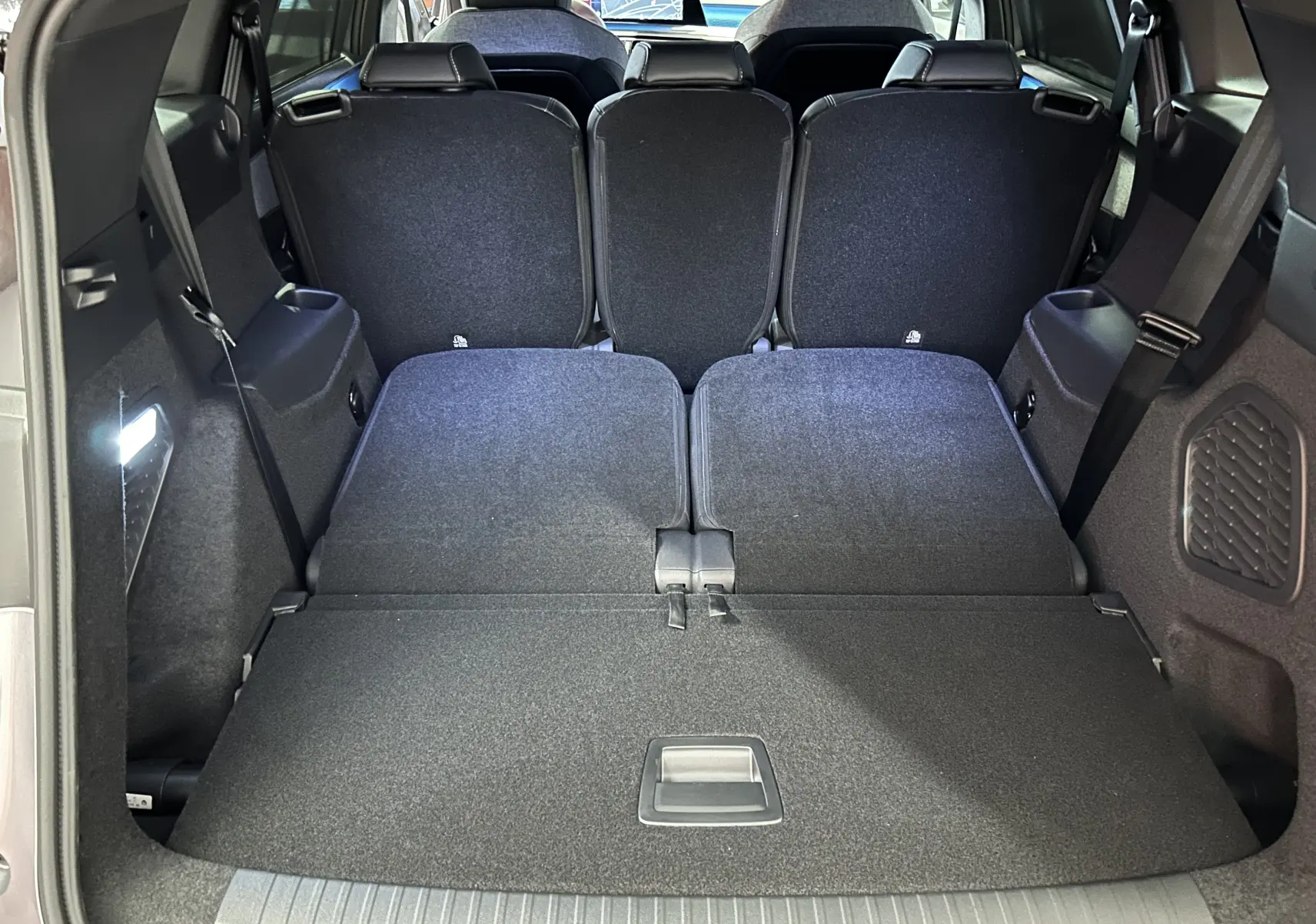 Coffre ouvert du Peugeot 5008 gris Artense montrant les sièges arrière rabattus et l'espace de chargement plat.