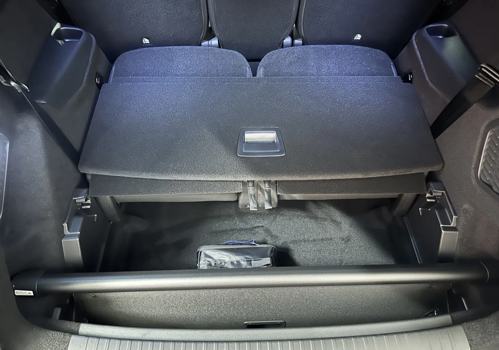 Coffre ouvert du Peugeot 5008 gris Artense, montrant le rangement sous plancher et la banquette arrière rabattue.