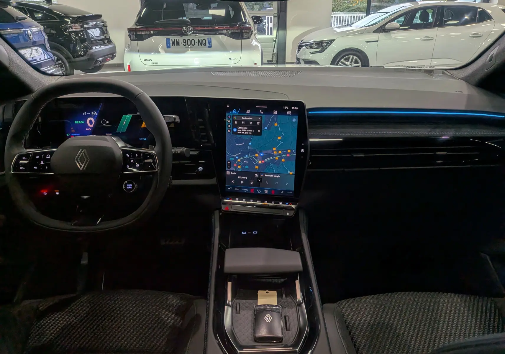 Intérieur du Renault Austral 2025 full hybride, tableau de bord noir avec grand écran tactile vertical et volant multifonction.