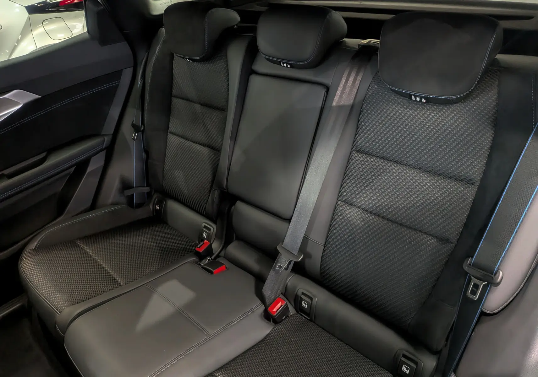 Vue rapprochée des sièges arrière noirs en tissu et cuir du Renault Austral 2025, avec ceinture de sécurité visible.