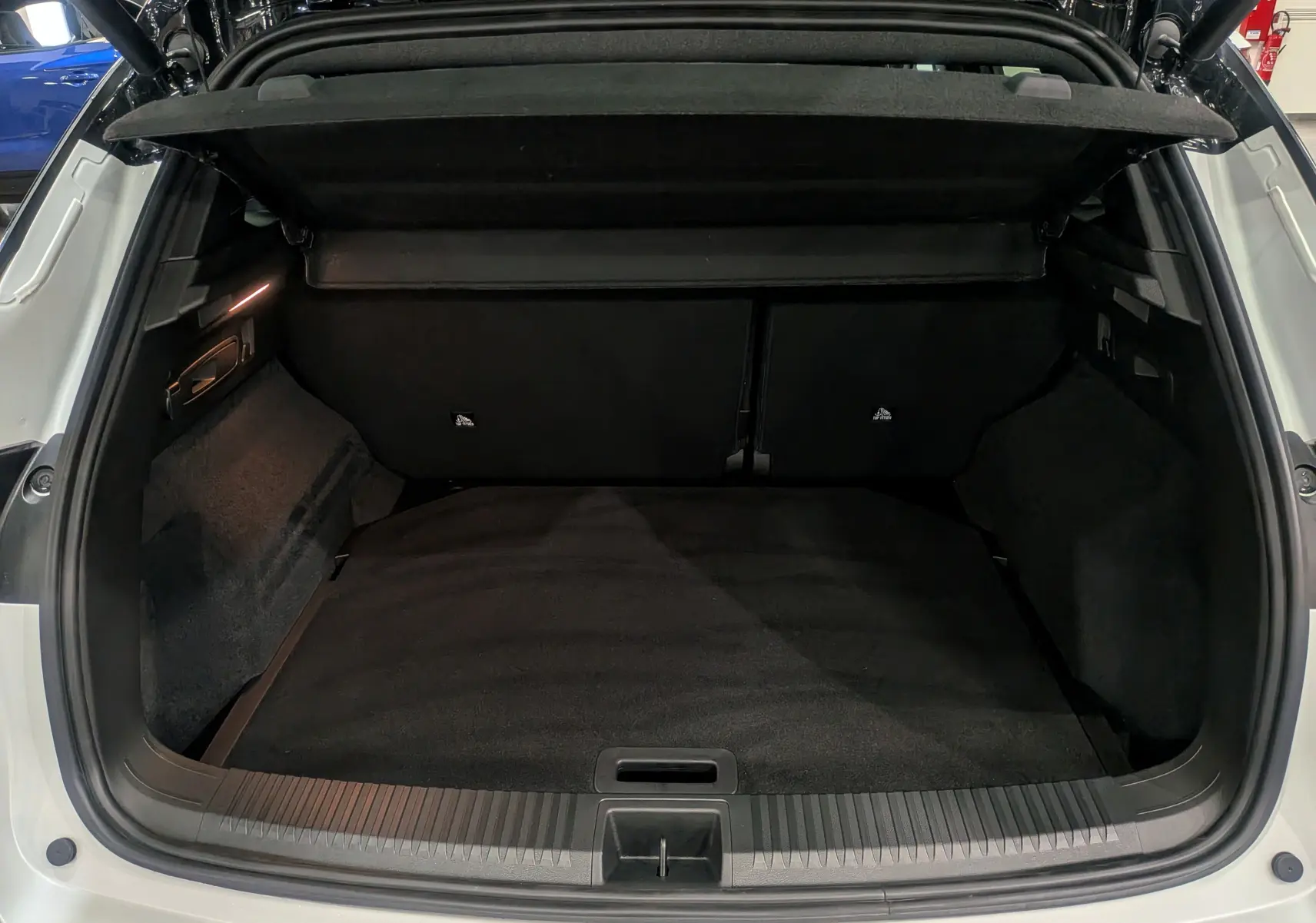 Coffre ouvert vu de l'arrière d'un Renault Austral blanc nacré satin avec intérieur noir et cache-bagages.