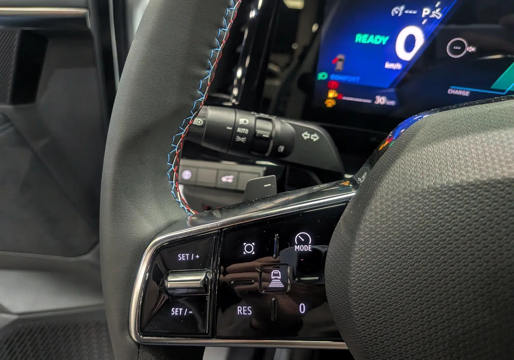 Gros plan sur le volant cuir du Renault Austral hybride avec commandes intégrées et tableau de bord digital allumé.