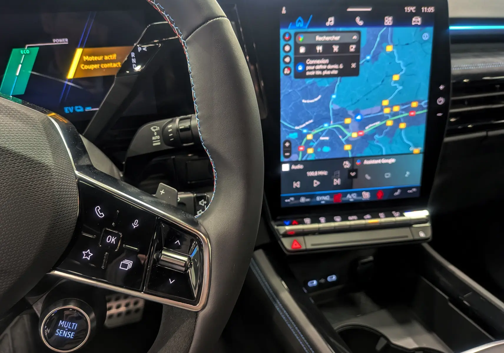 Intérieur du Renault Austral hybride 2025, vue sur le volant avec commandes tactiles et écran central tactile affichant la navigation.