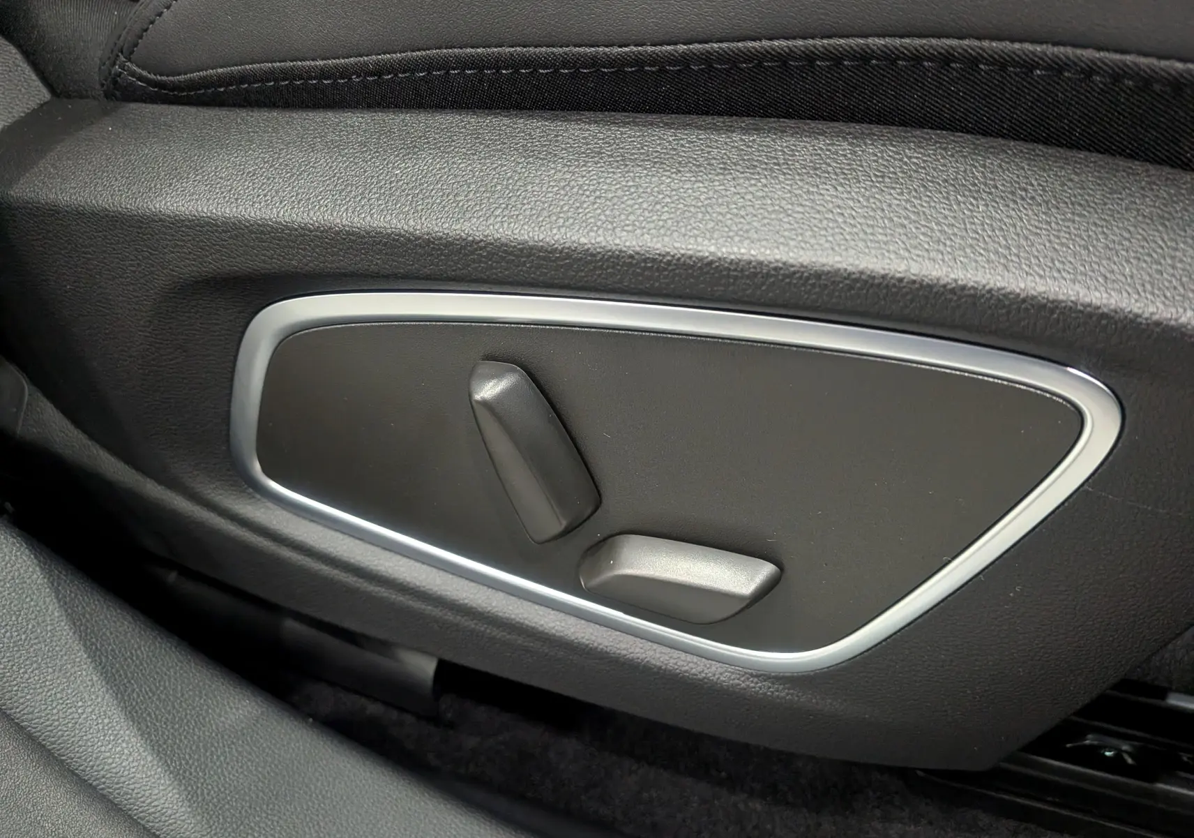 Gros plan sur les commandes de réglage électrique du siège côté gauche du Renault Austral blanc nacré 2025.