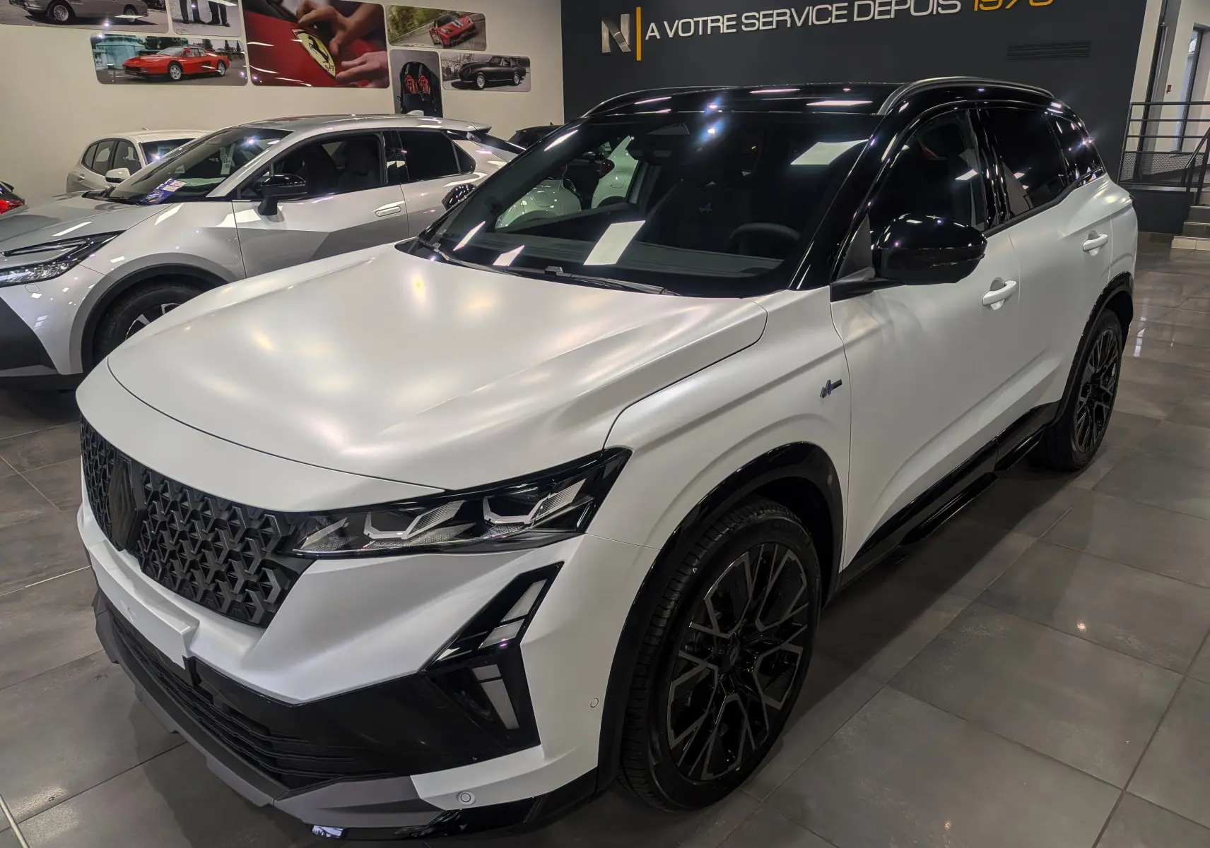 Renault Austral blanc nacré satin avec toit noir, vue 3/4 avant droit, calandre noire et jantes noires distinctives.