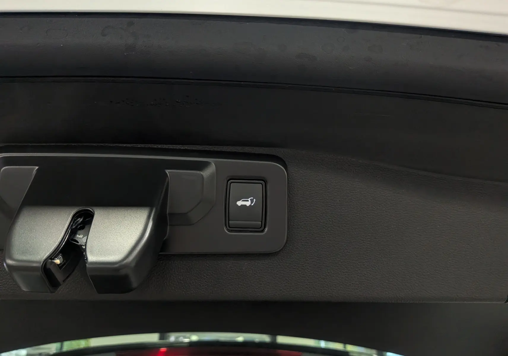 Bouton d'ouverture électrique du hayon sur le coffre intérieur du Renault Austral blanc nacré 2025.