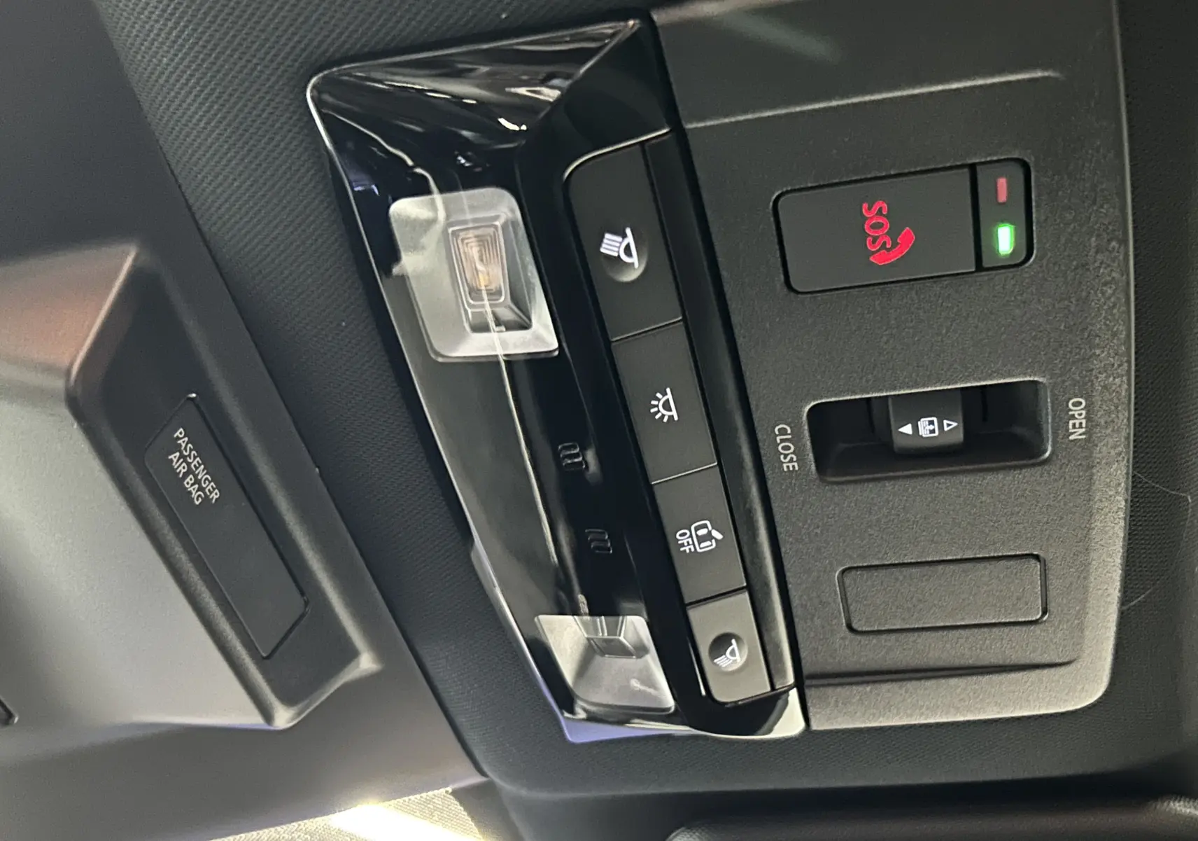 Vue en gros plan du panneau de commandes au plafond du Nissan Qashqai 2025, avec bouton SOS rouge et éclairage intégré.