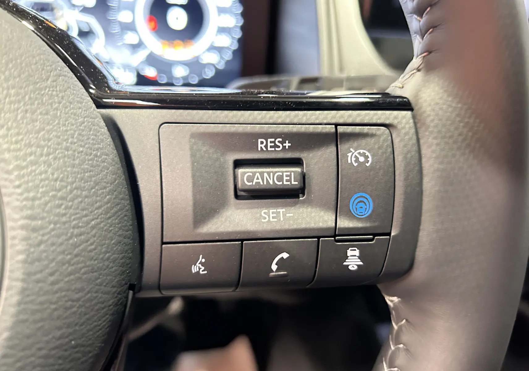 Gros plan sur les commandes de régulateur de vitesse au volant noir du Nissan Qashqai gris céramique 2025.