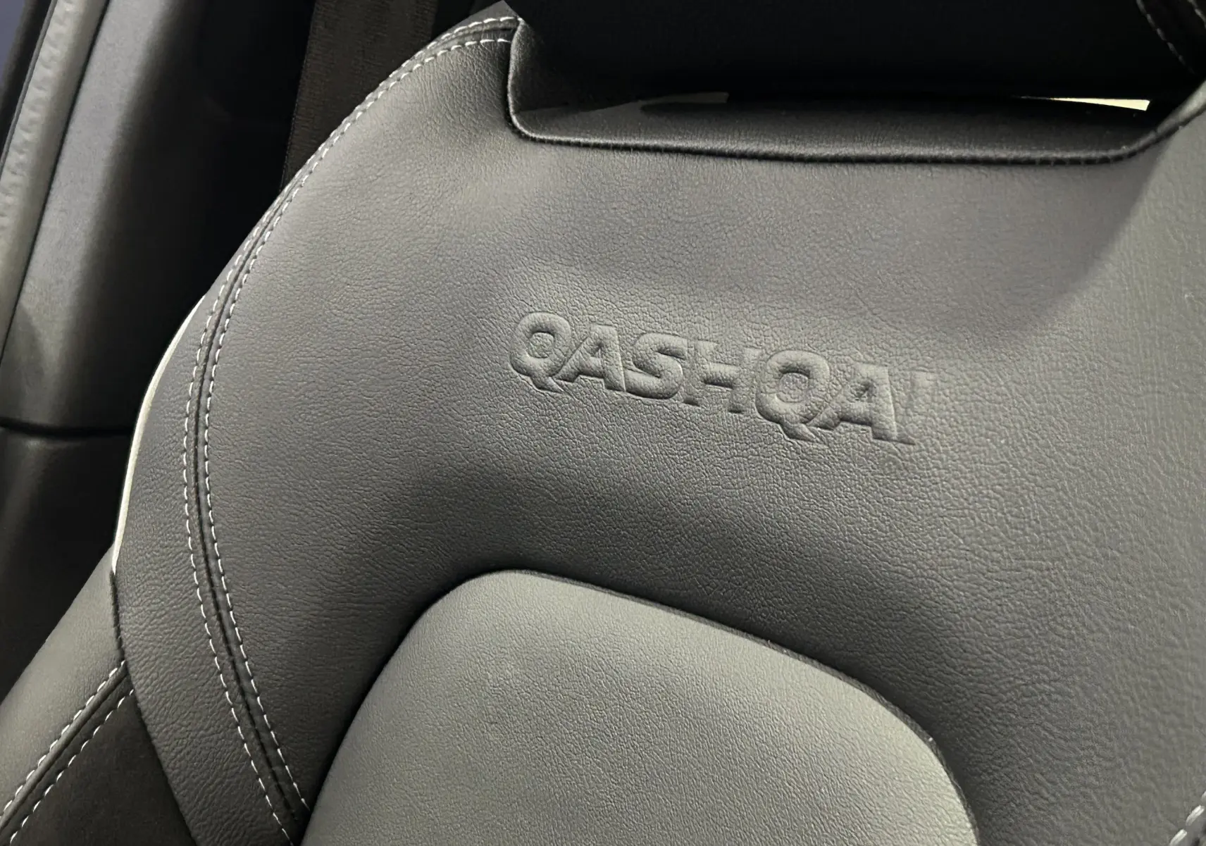 Gros plan sur l'appui-tête noir en cuir embossé du Nissan Qashqai 2025, soulignant le logo du modèle.