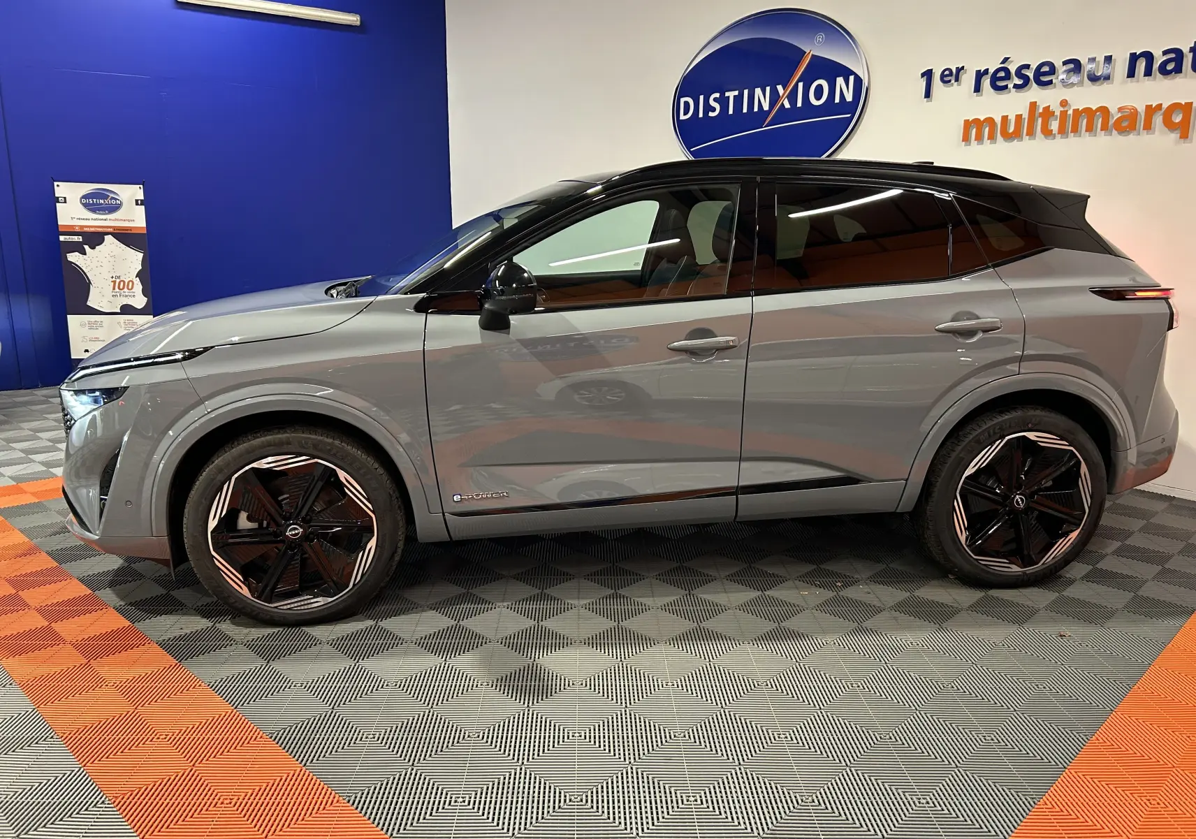 Vue de profil côté gauche du Nissan Qashqai 2025 gris céramique métal avec toit noir panoramique et jantes noires distinctives.