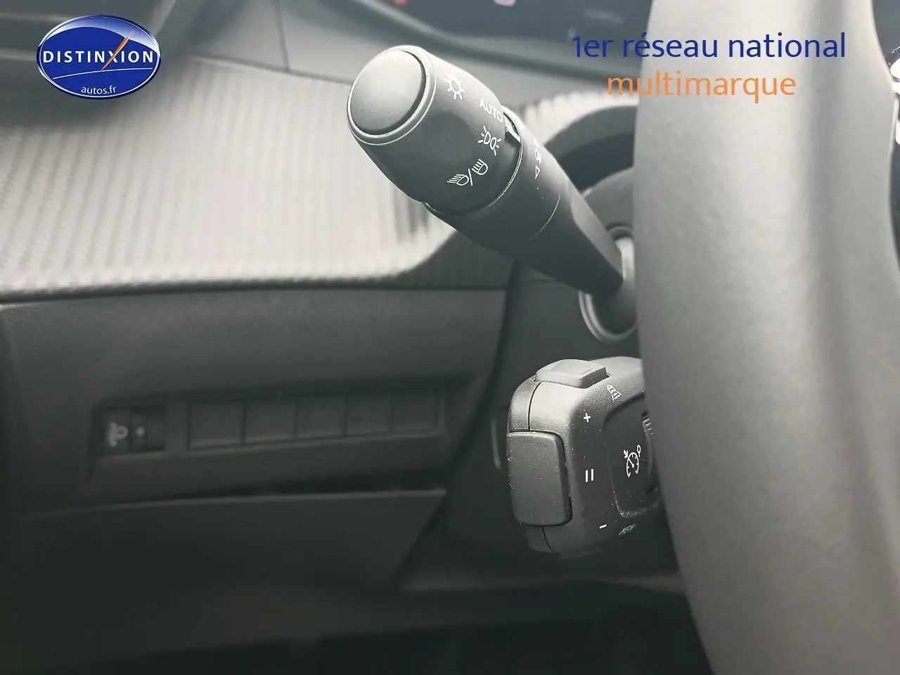 Gros plan sur la commande des phares et régulateur de vitesse derrière le volant d’un Peugeot 2008, intérieur noir.