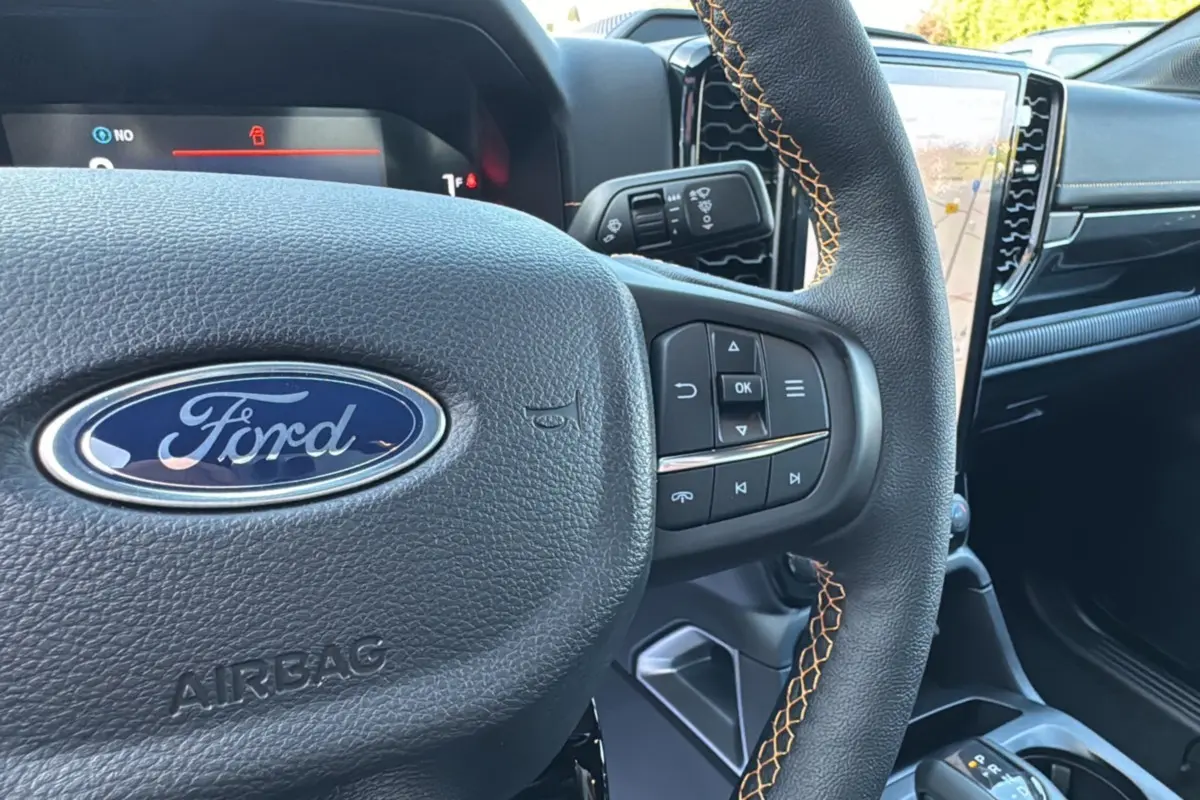 Gros plan sur le volant cuir noir avec surpiqûres orange et tableau de bord du Ford Ranger PHEV 281 Wildtrak 2025.