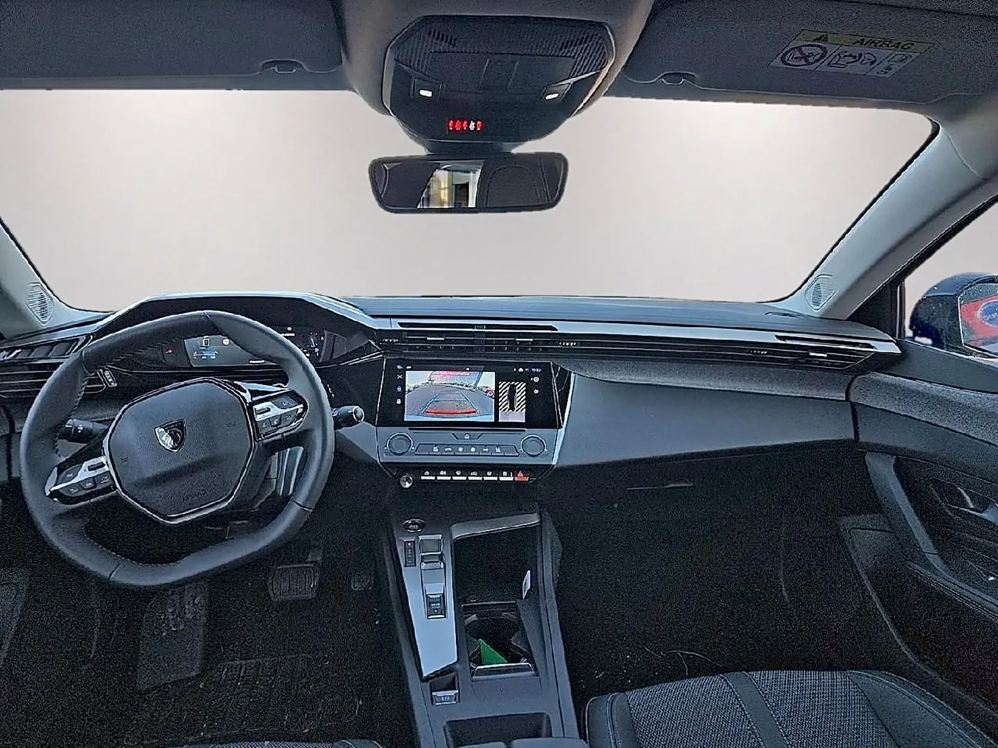 Vue intérieure avant du tableau de bord et volant noir du Peugeot 308 SW 1.5 BlueHDi 130 Gris Artense 2025.